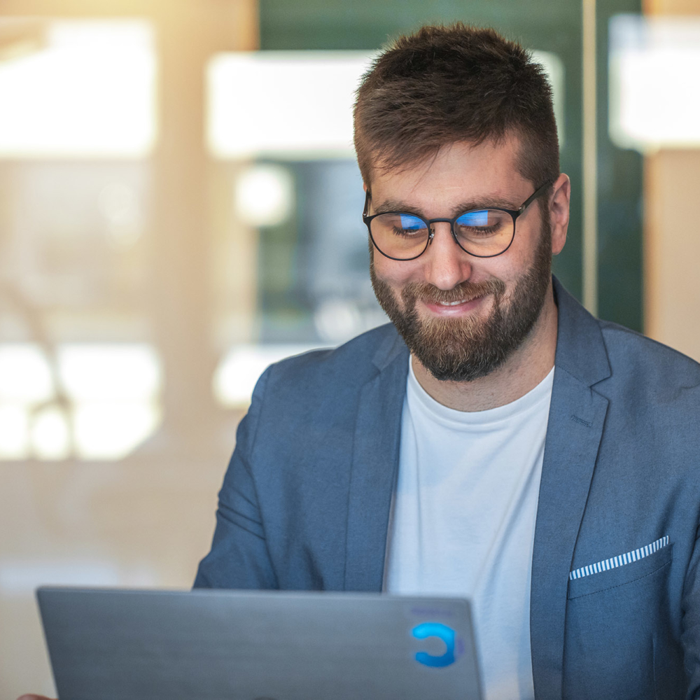 Focus on a smiling consultant in a workroom looking at his laptop