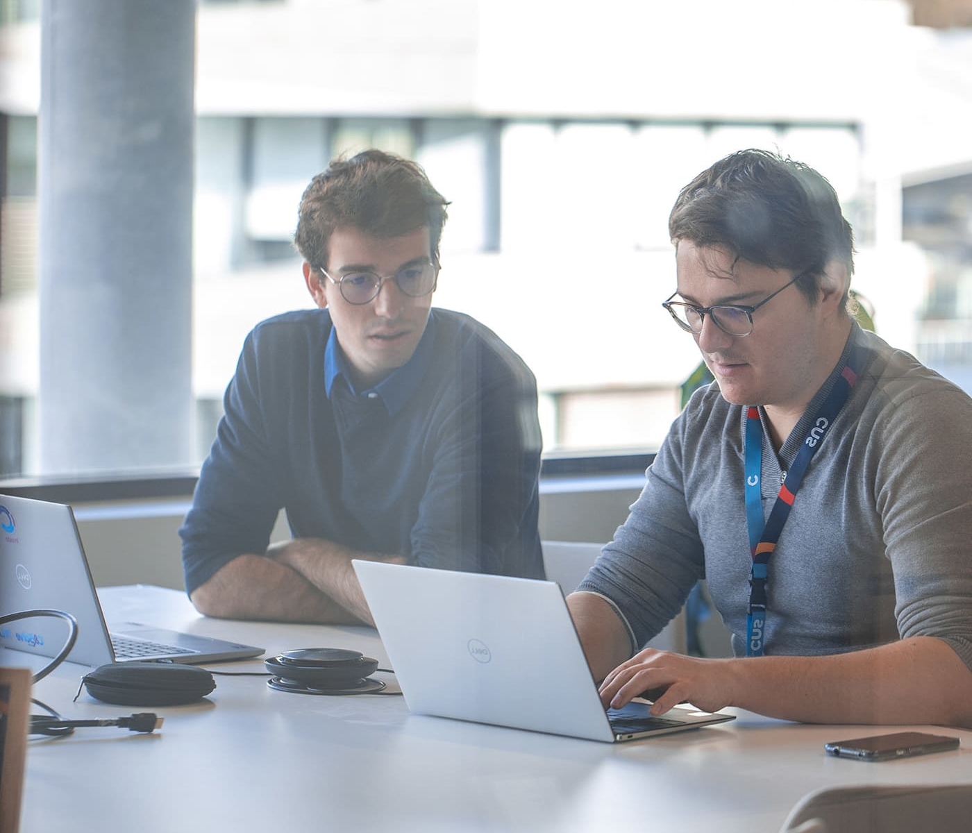 Two consultants CNS met in a modern meeting room to review a client project. Photo taken through a glass